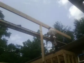 Carpenter setting a ridge beam over a new addition frame — Ice Dam Removal by Roofing Brothers in Geff