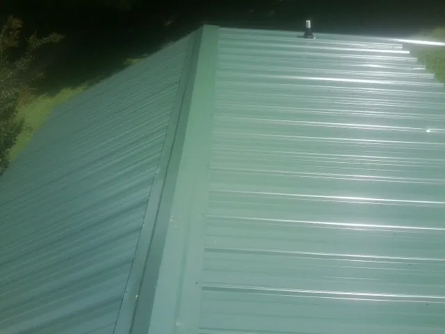 New green metal panels meeting at the ridge of a roof — Flat Roof Repair work by our crew in Geff