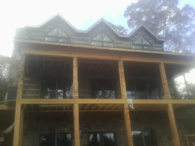 Dormers and porch framing on a large log home under construction — Roof Coating work by our crew in Geff