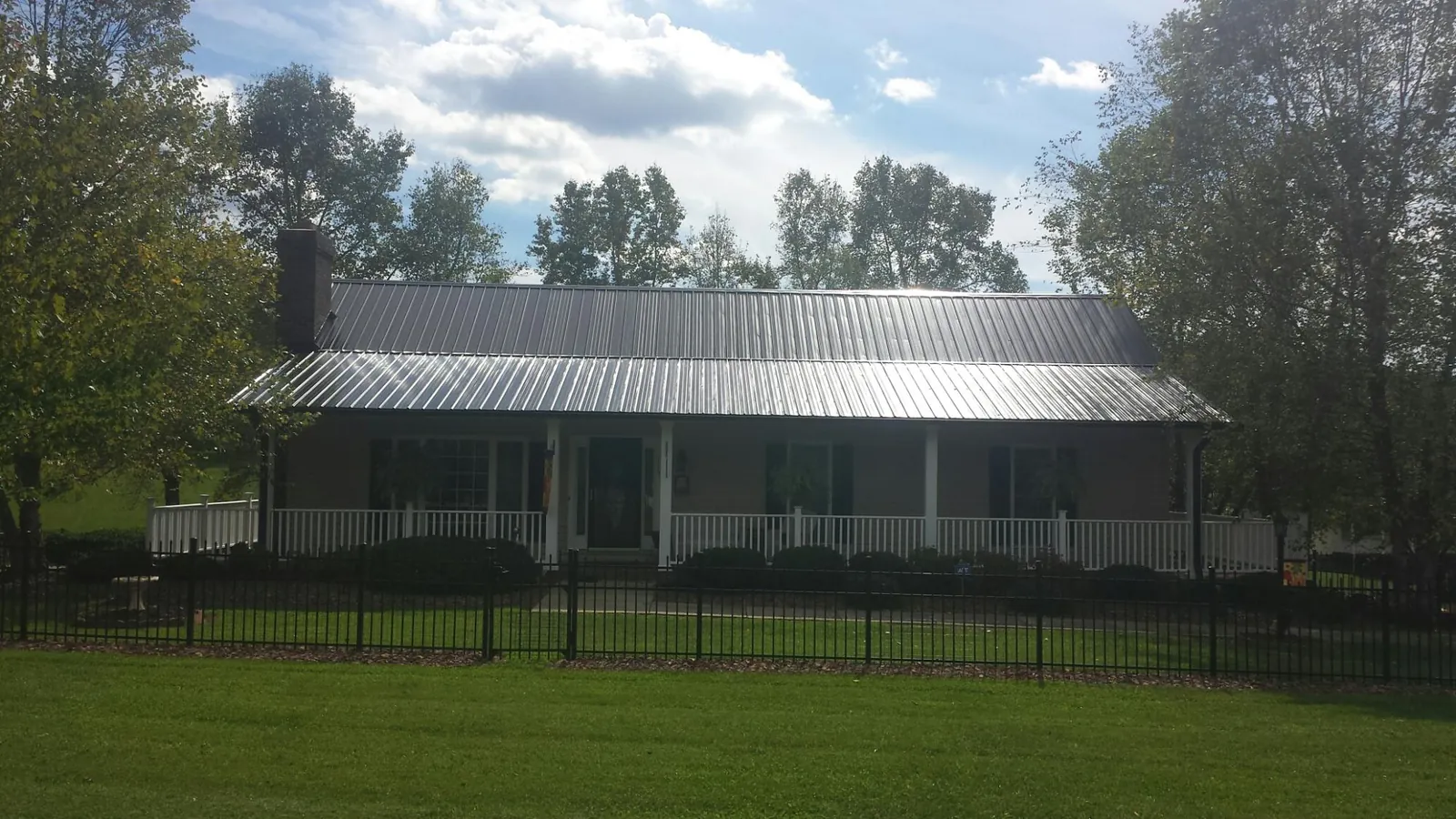 Gray metal roof on a brick ranch with a full width front porch — Gutter Guard Installation work by our crew in Geff