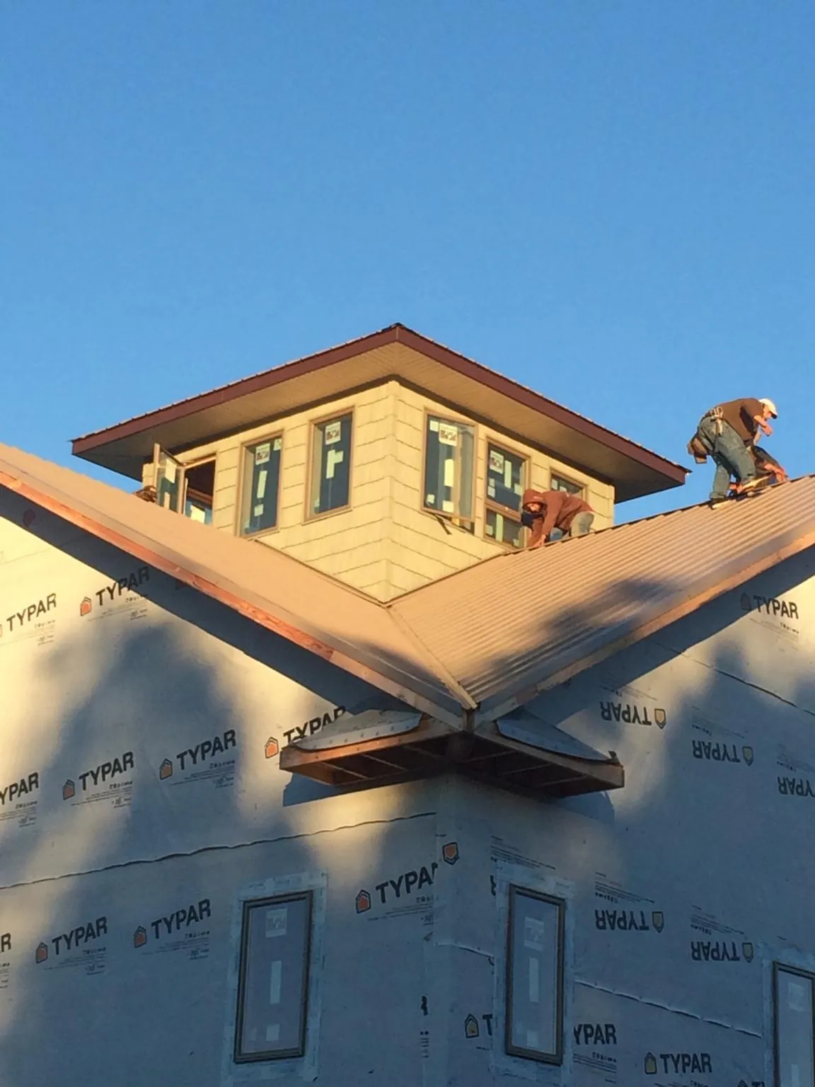 Roofers working around a rooftop cupola on a new metal roof at sunset — Roof Waterproofing in Geff by Roofing Brothers